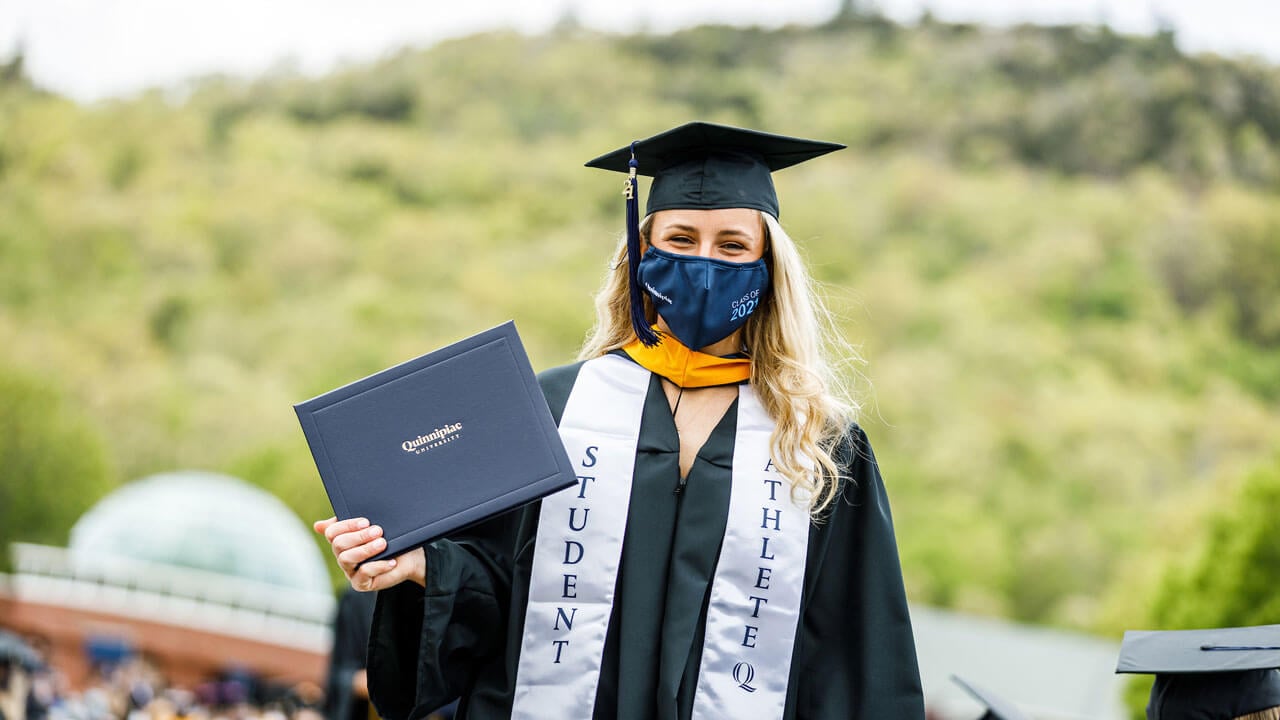 A graduate proudly holds up her Quinnipiac diploma cover