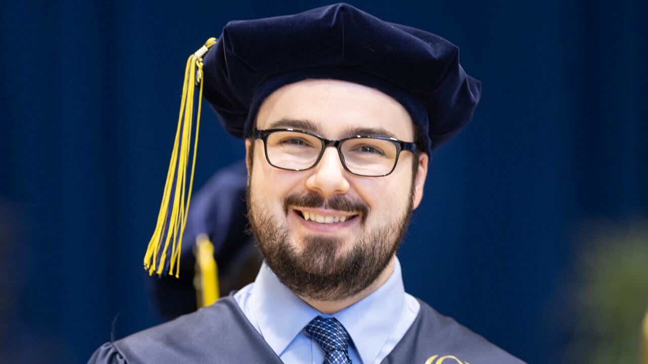 Medicine graduate smiling, showing of Class of 2024 tassel on cap