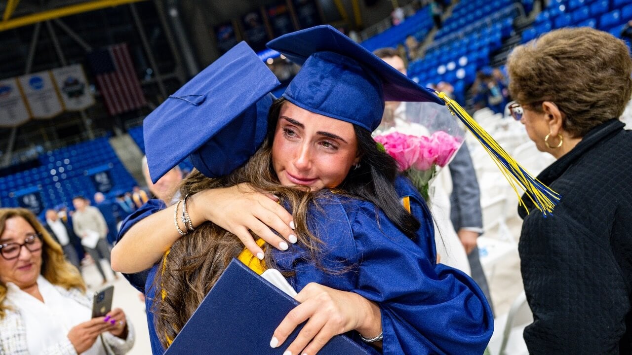 Two graduates hug at the end of the Commencement ceremony