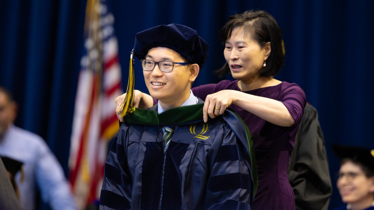 A medical graduate receives his doctoral hood on stage