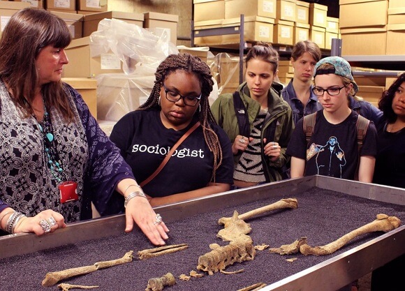 Quinnipiac students study a centuries-old skeleton with the curator at the Museum of London.