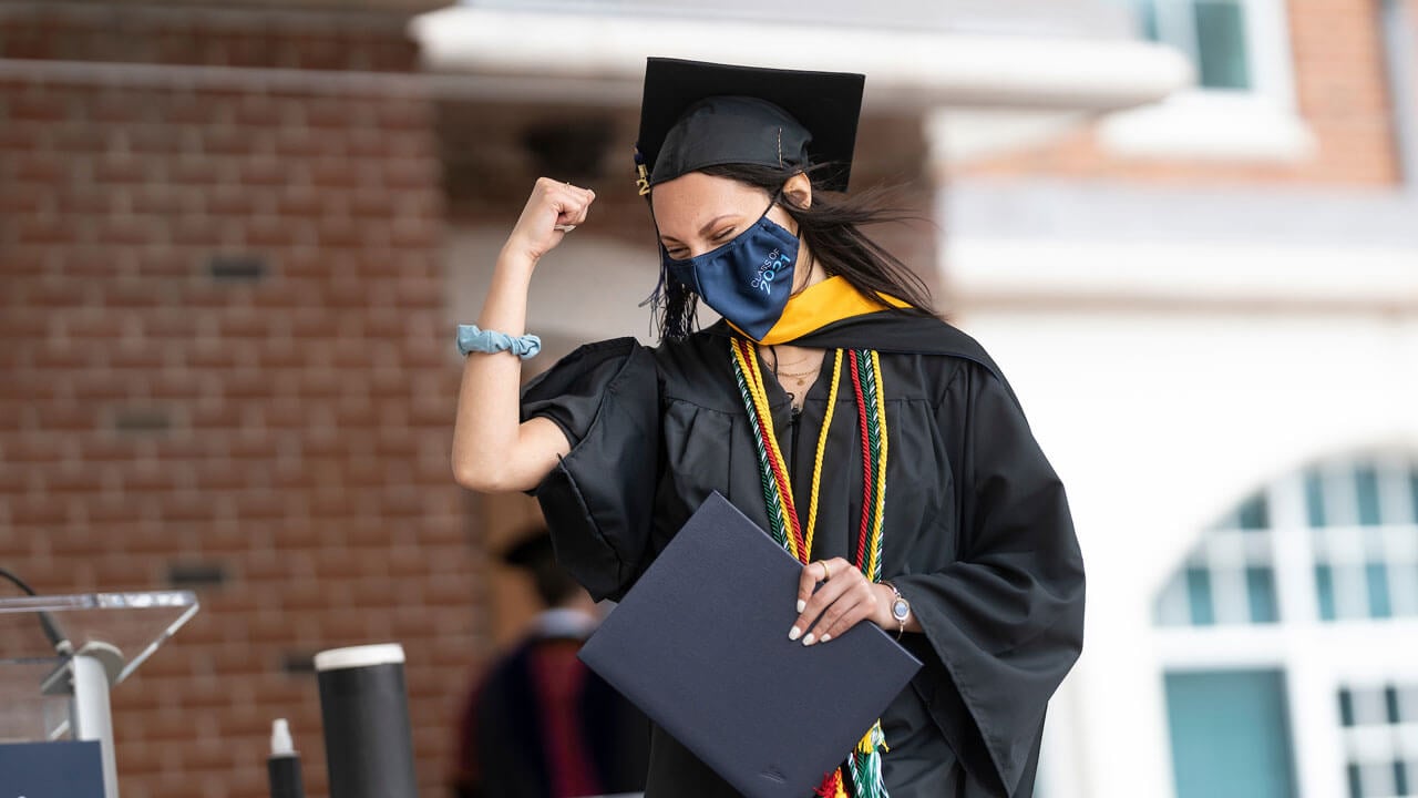A graduate pumps her fist in victory as she crosses the stage.