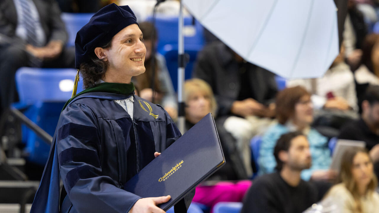Class of 2024 medicine student smiles while holding their diploma