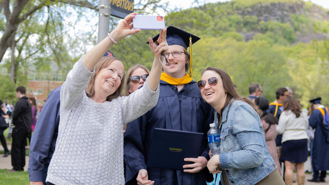 Family takes a selfie with a graduate student in their cap and gown