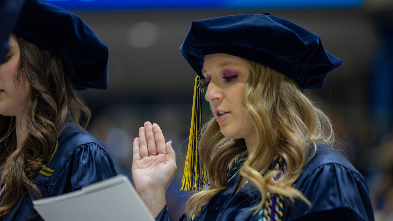 Law graduate from the class of 2024 raises a hand while reciting the professional oath.