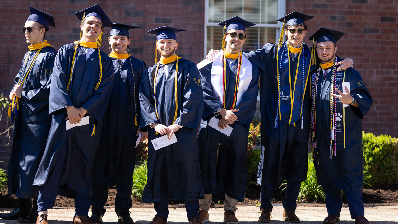Half a dozen graduates pose arm in arm for a photo