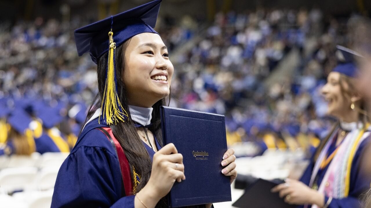 Graduate holding up their diploma and smiling
