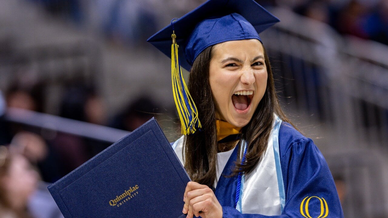 Graduate smiles with their degree.