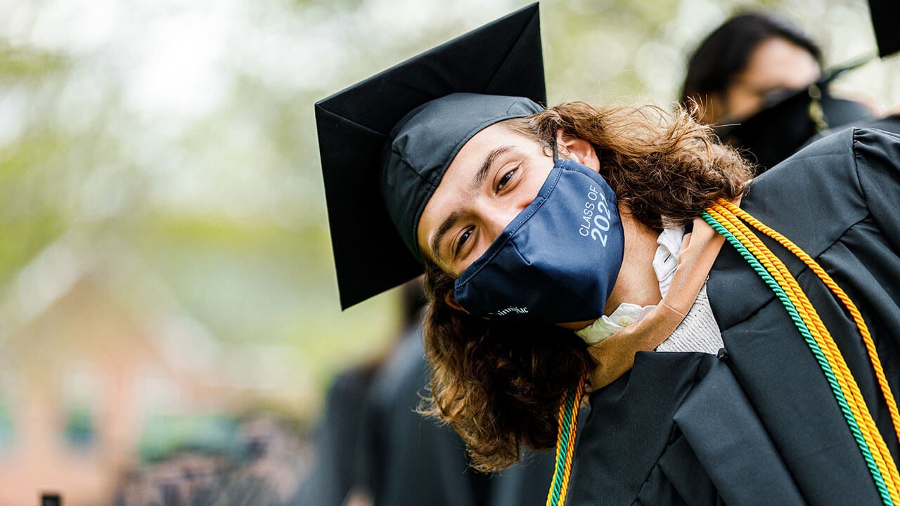 Student smiling at camera while in line at commencement ceremony