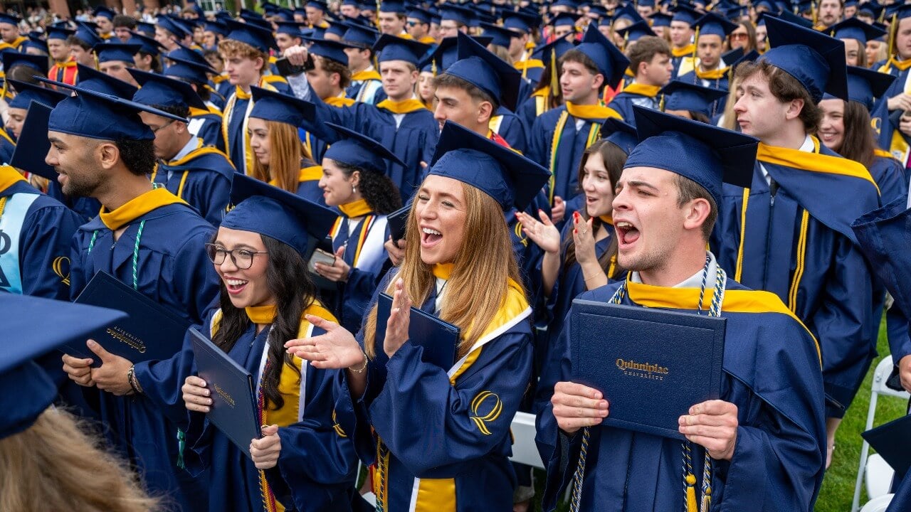 Crowd of graduates cheering and clapping for their peers
