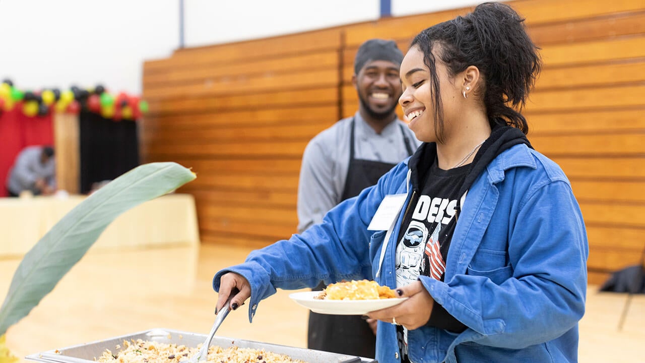 Student scoops food onto her plate at an event