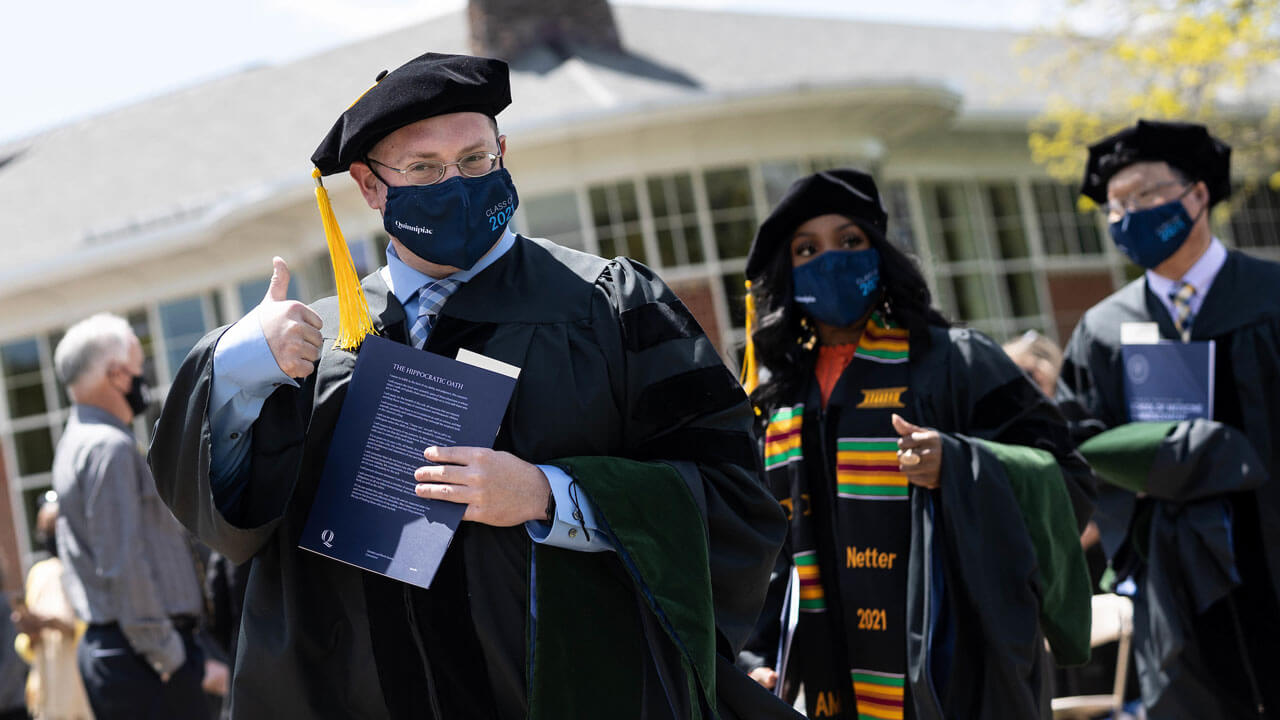 Medical school graduate giving thumbs up after graduating