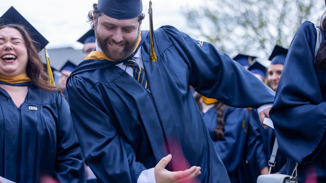 A graduate enthusiastically gestures a Bobcat paw swipe