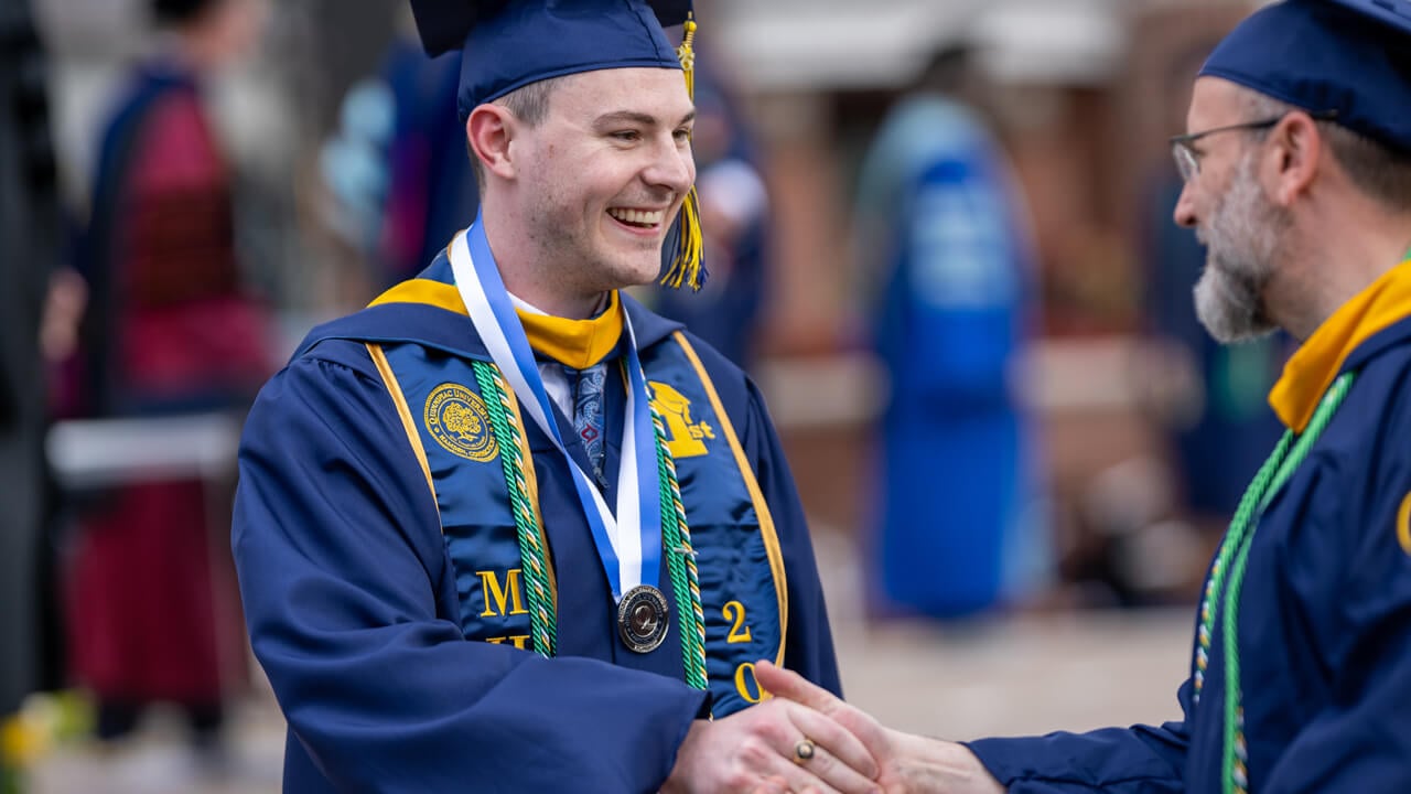 Graduates smile and shake hands