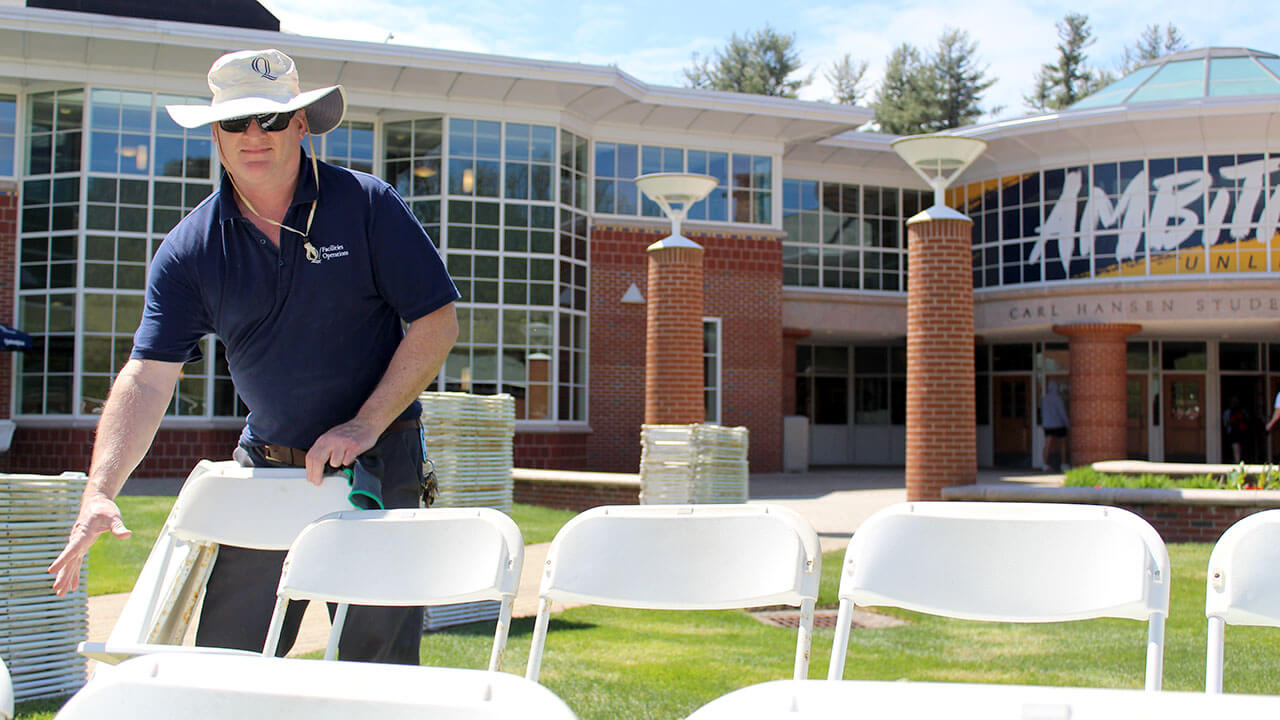 Facility worker sets up chairs for Commencement