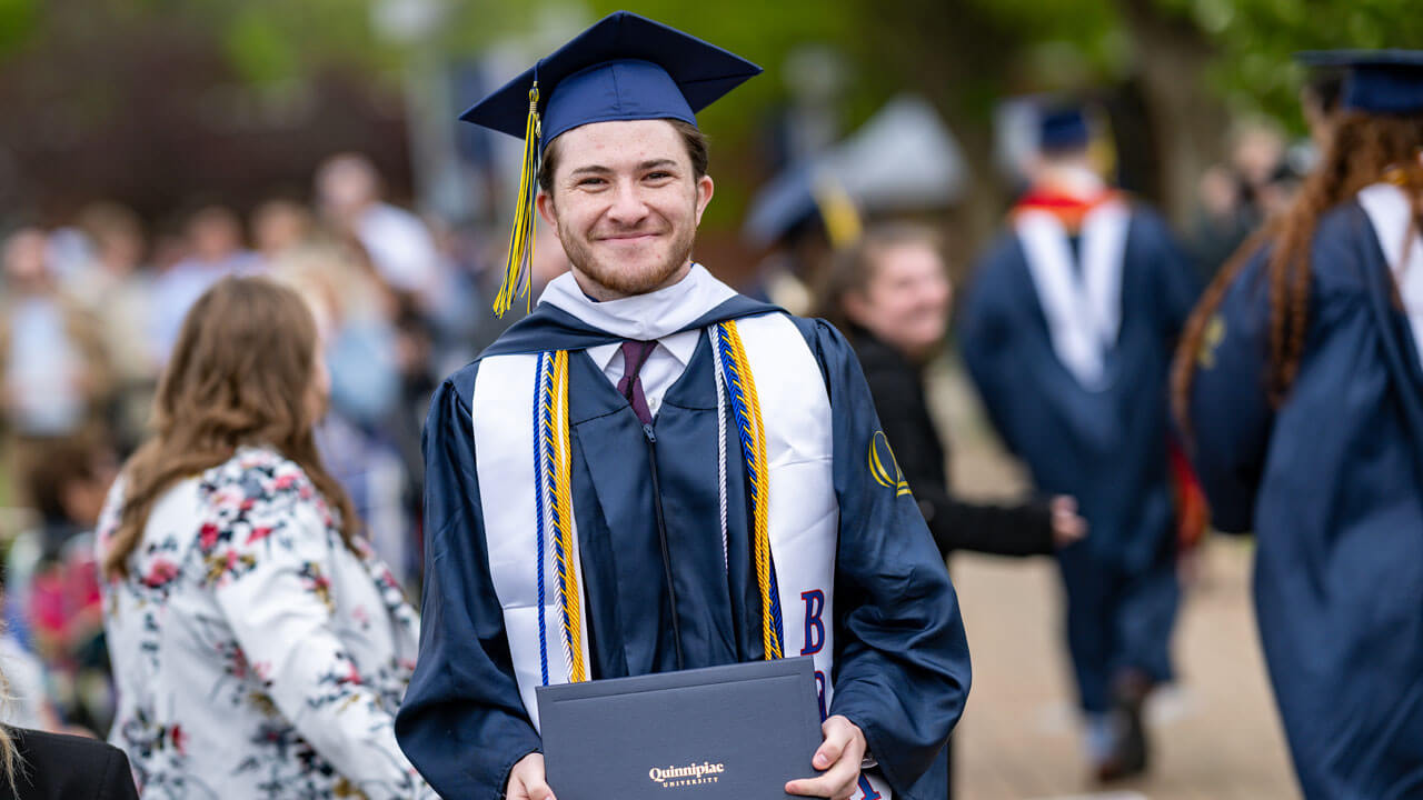 Quinnipiac graduate shows off their degree smiling