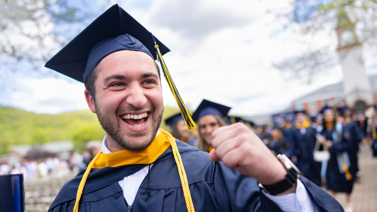A graduate cheers and pumps his fist in celebration