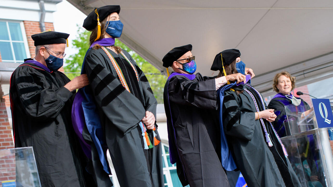 Faculty members put on the new graduates doctoral hoods