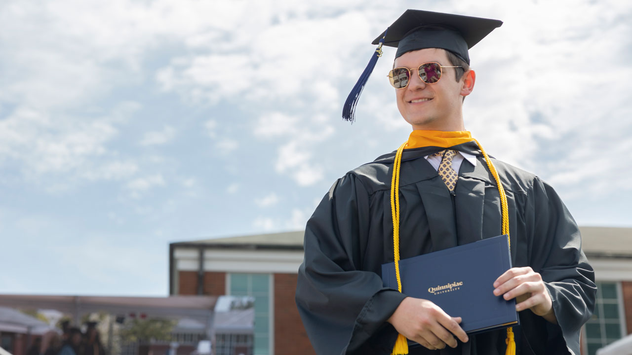 Graduate holds diploma while wearing sunglasses