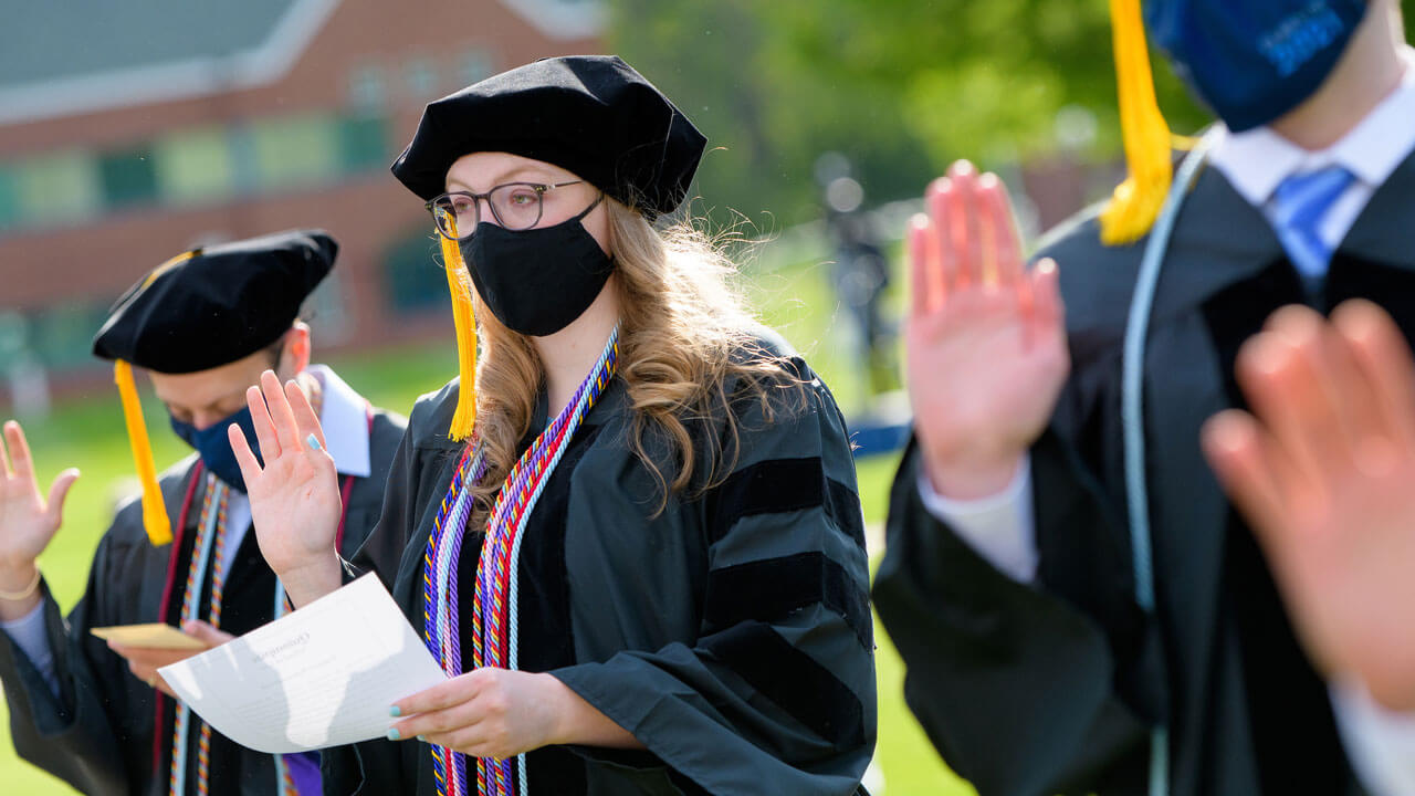A graduate raises her hand as she recites an oath
