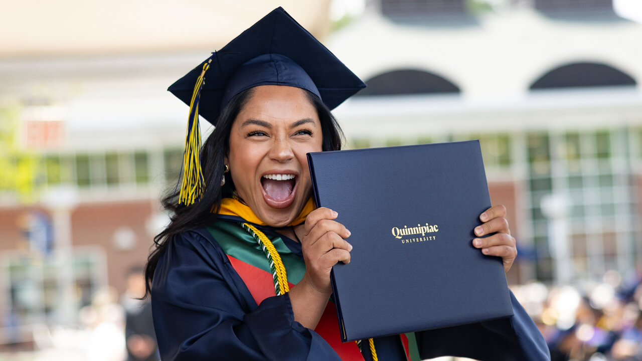 Student smiles holding degree