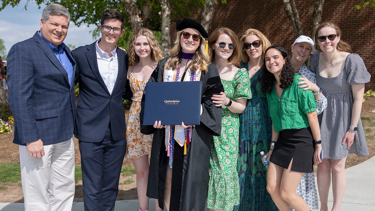 Family and friends surround graduate for a photo with diploma