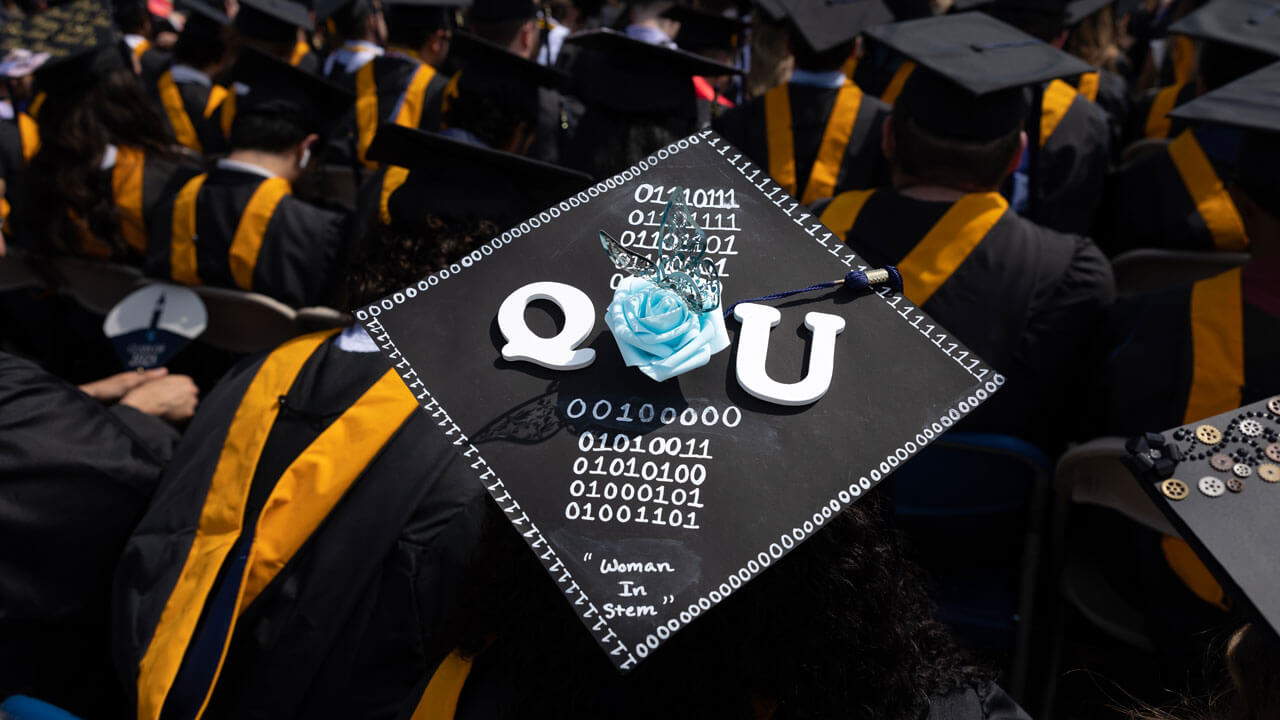 Artsy photograph of graduates cap decorated saying "QU"