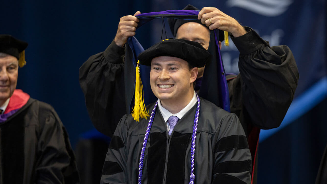 A graduate receives his hood during Commencement