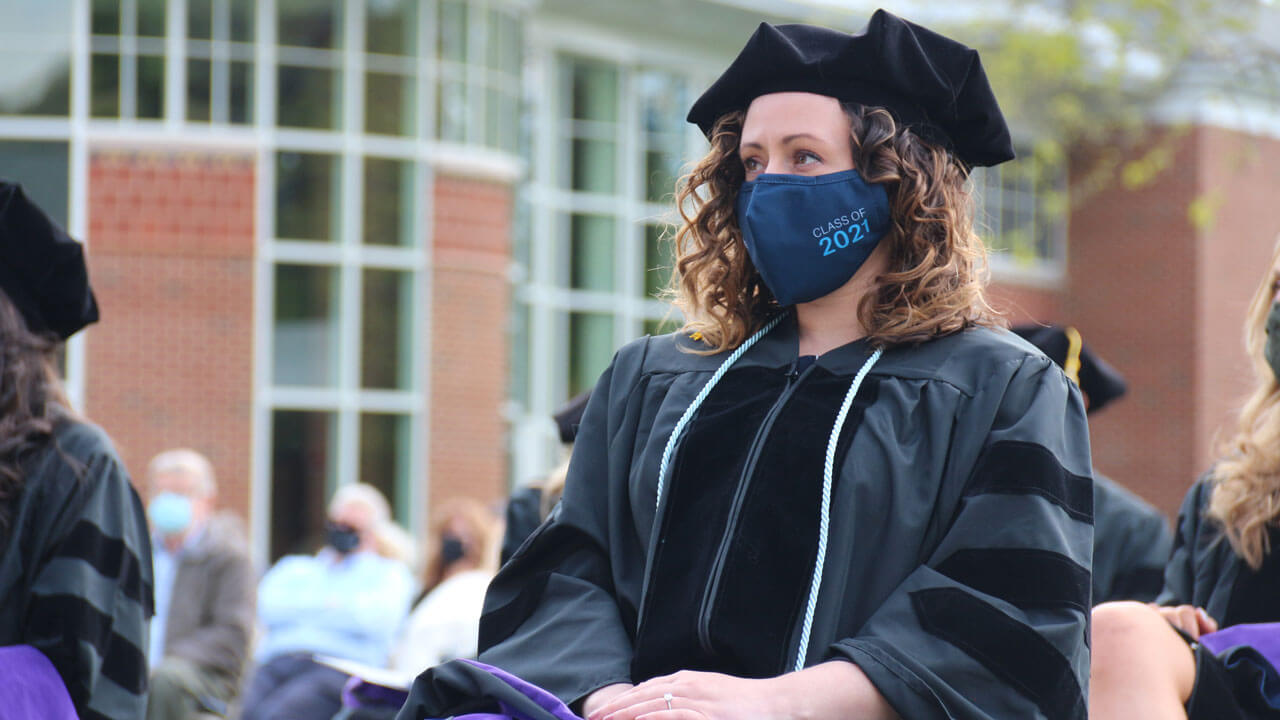 A graduate sits and listens during the Commencement ceremony