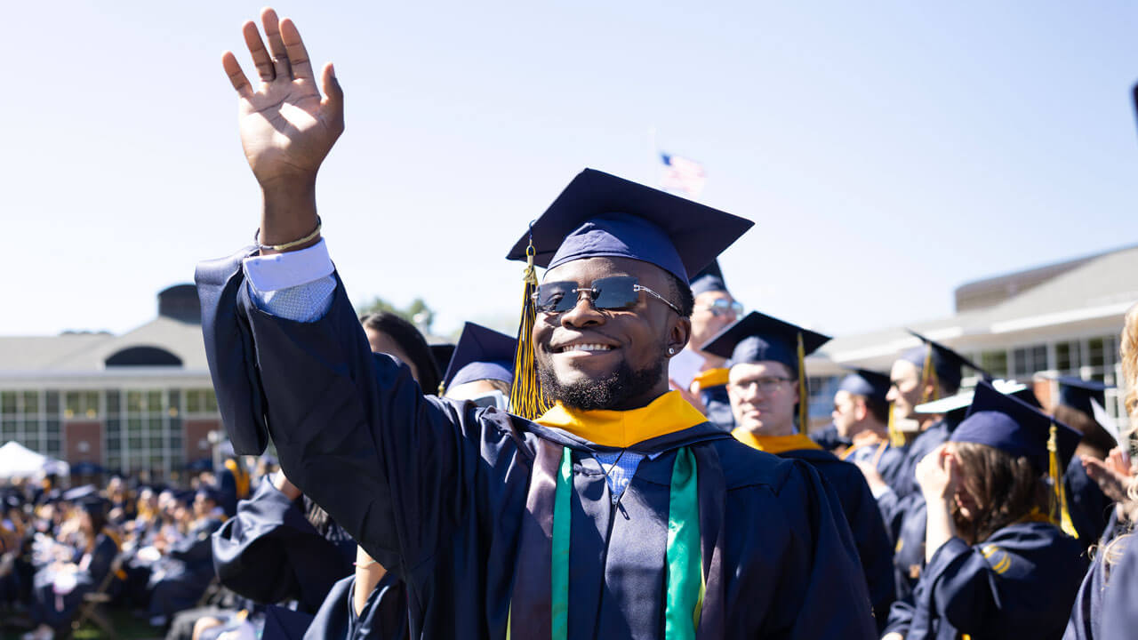 Graduate smiling while waving to the crowd