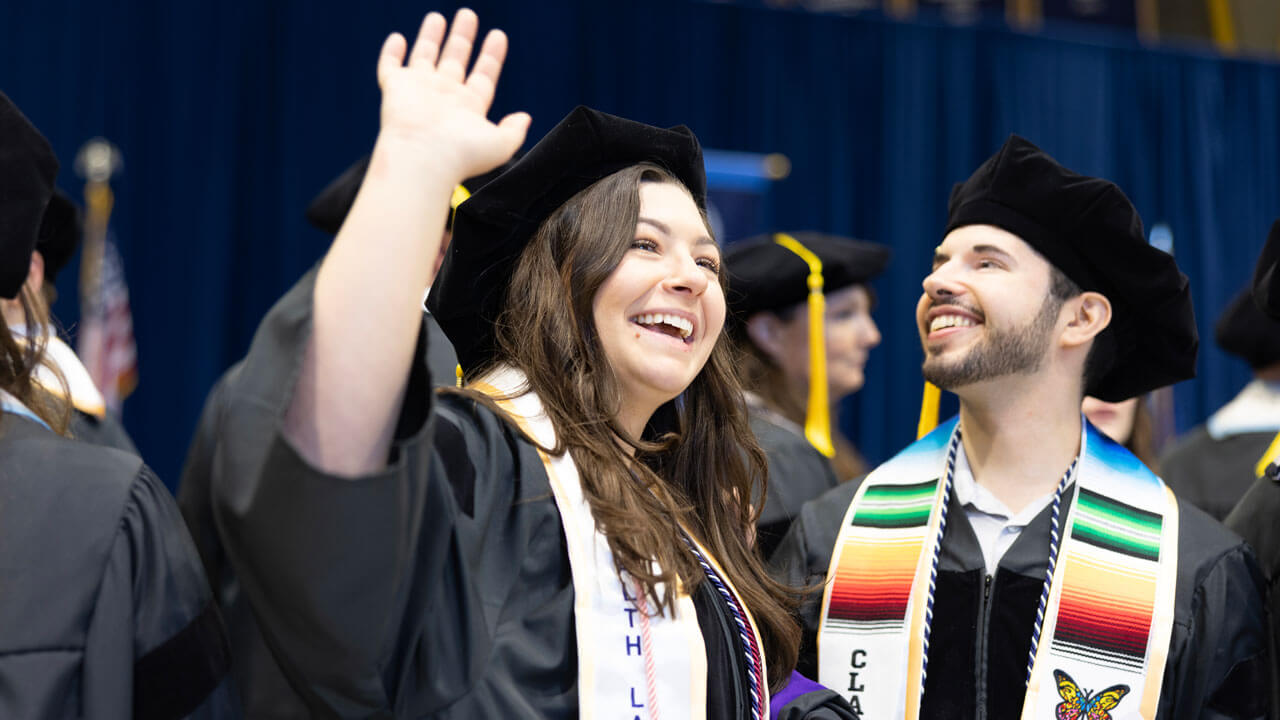 Students wave to audience during Law commencement