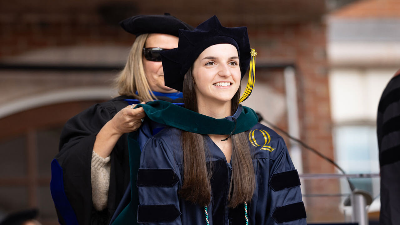 During the Commencement ceremony, a 2024 Health Sciences graduate receives a green hood.