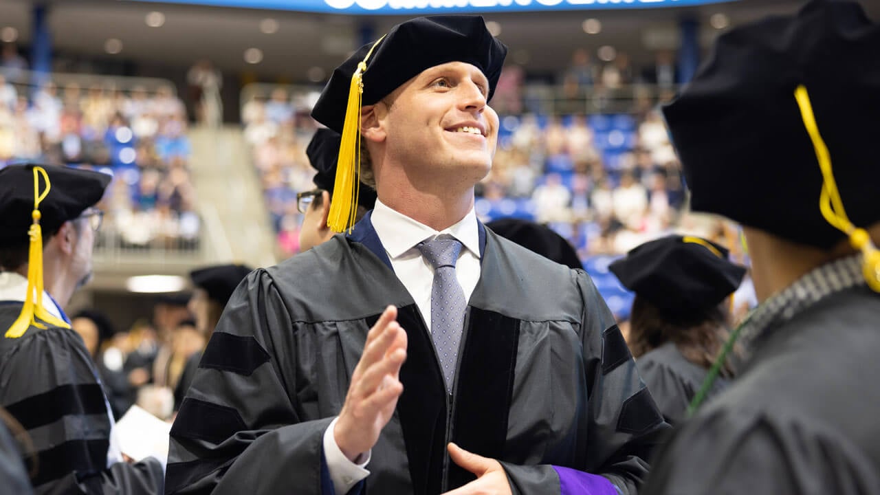 Student admiringly gazes to the audience smiling during Law commencement