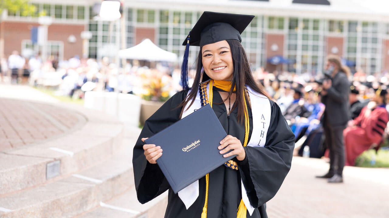 Graduate smiling with joy while holding her diploma
