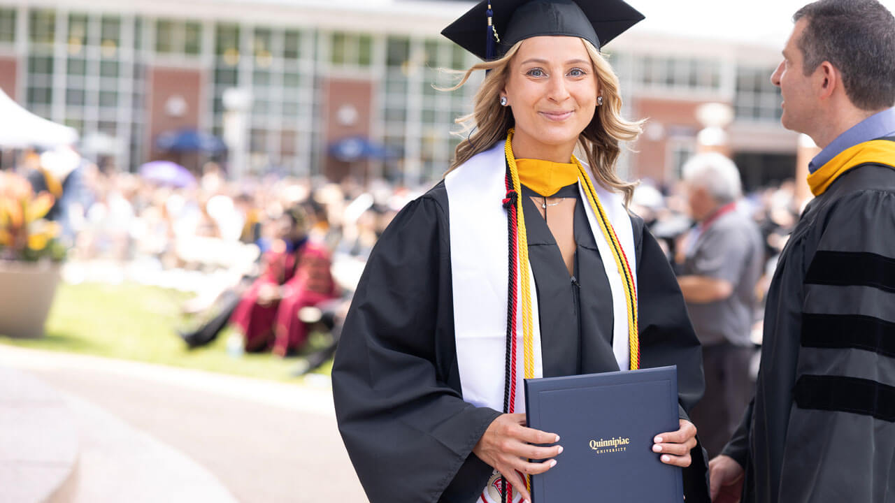 Graduate happily holds her diploma while walking across stage