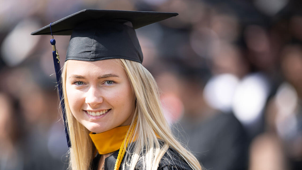 female graduate smiles confidently at the camera