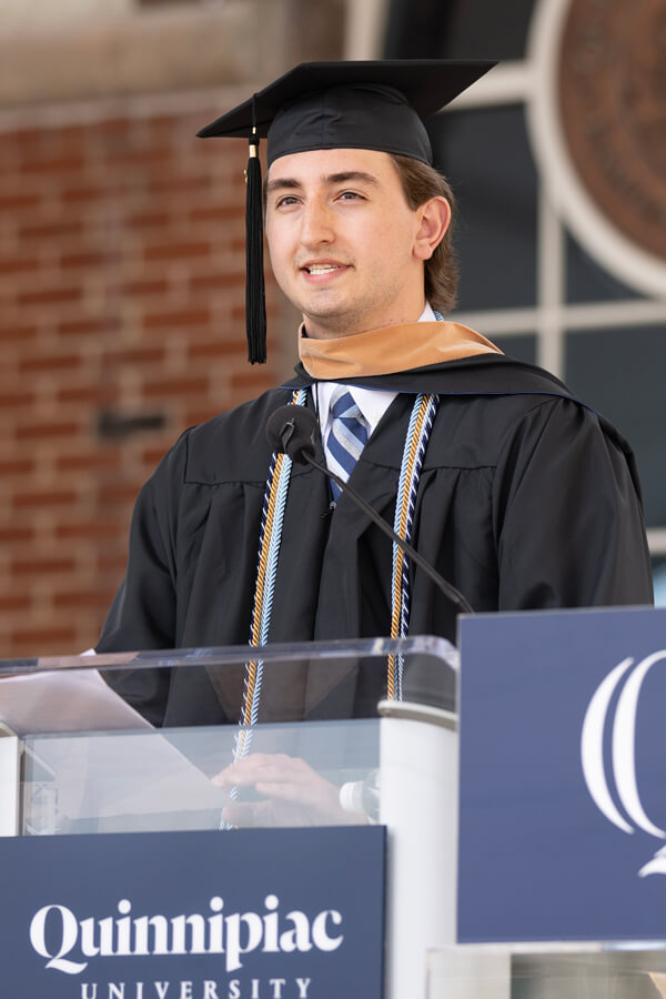 Cameron Davignon speaks at a podium in front of the library