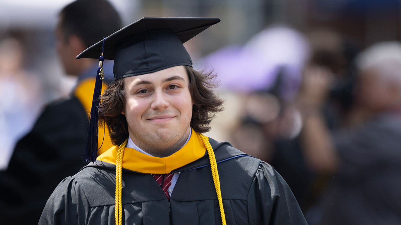 male graduate smiles slightly at the university