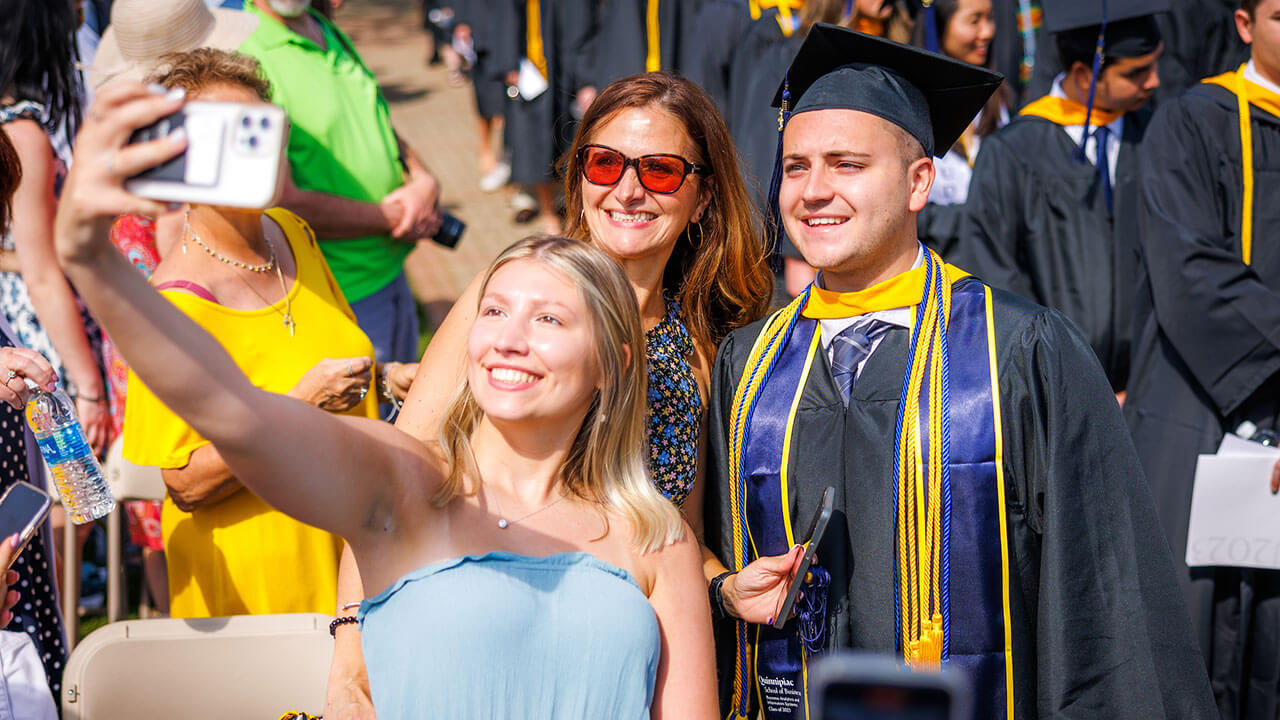 Graduate takes a photo with their friends at Commencement