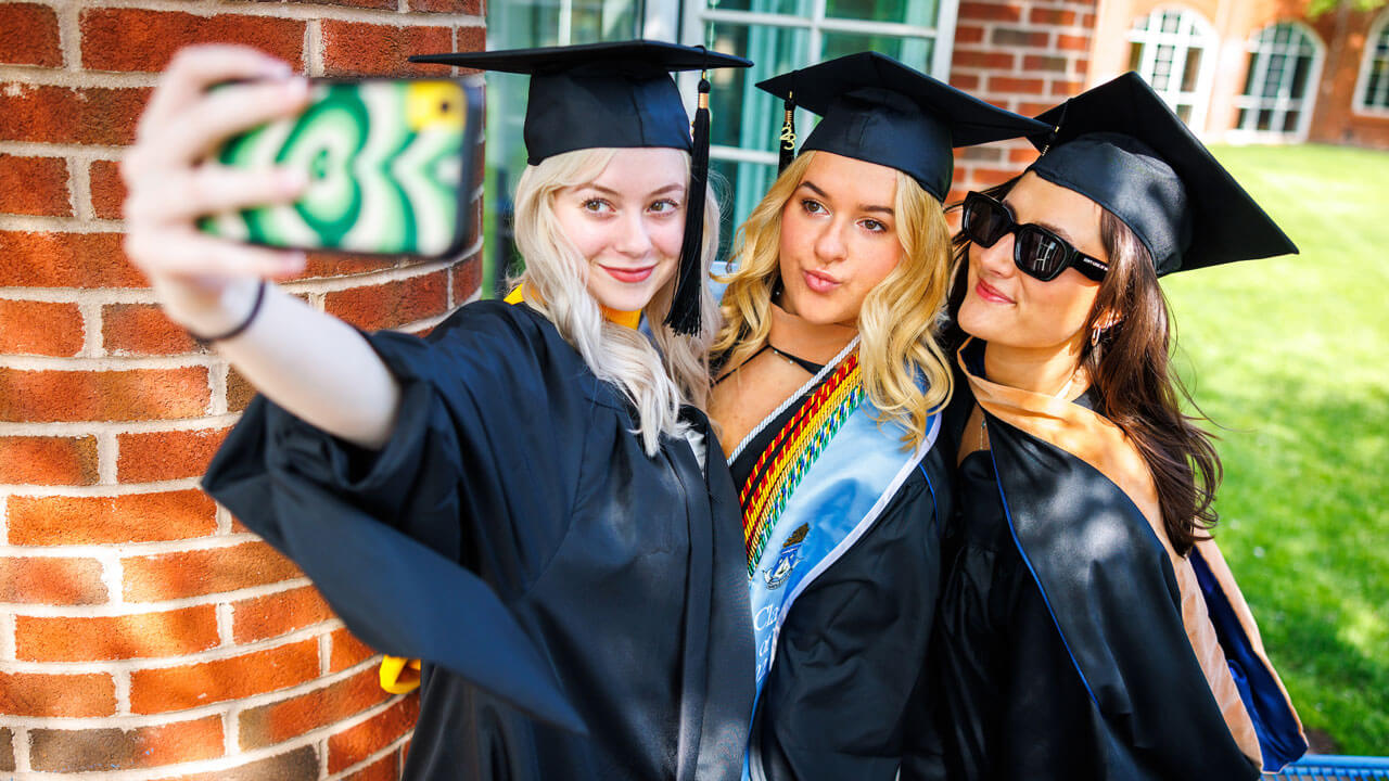 Busines graduates taking selfie photos prior to graduation ceremony