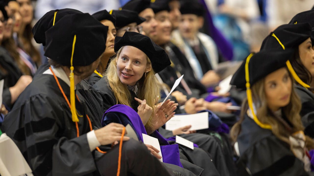 Students seated and whispering during Law Commencement