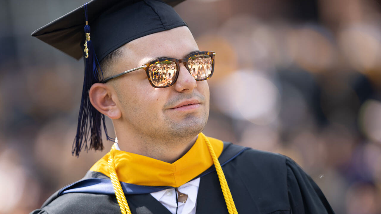 Graduate with sunglasses on looking into the distance