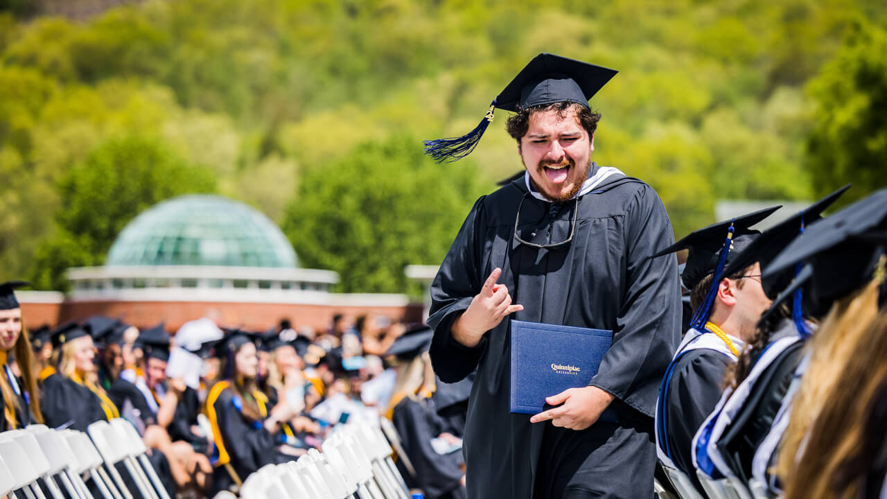A graduate celebrates as he walks back to his seat