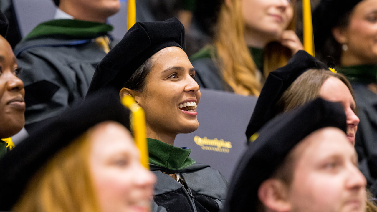 Dozens of graduates smile and pose with their diplomas