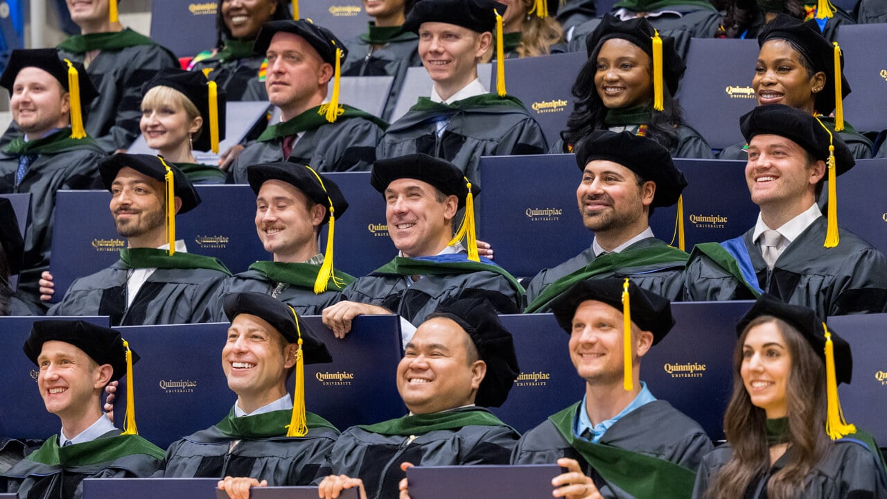 Dozens of medical graduates hold their diplomas for a class photo
