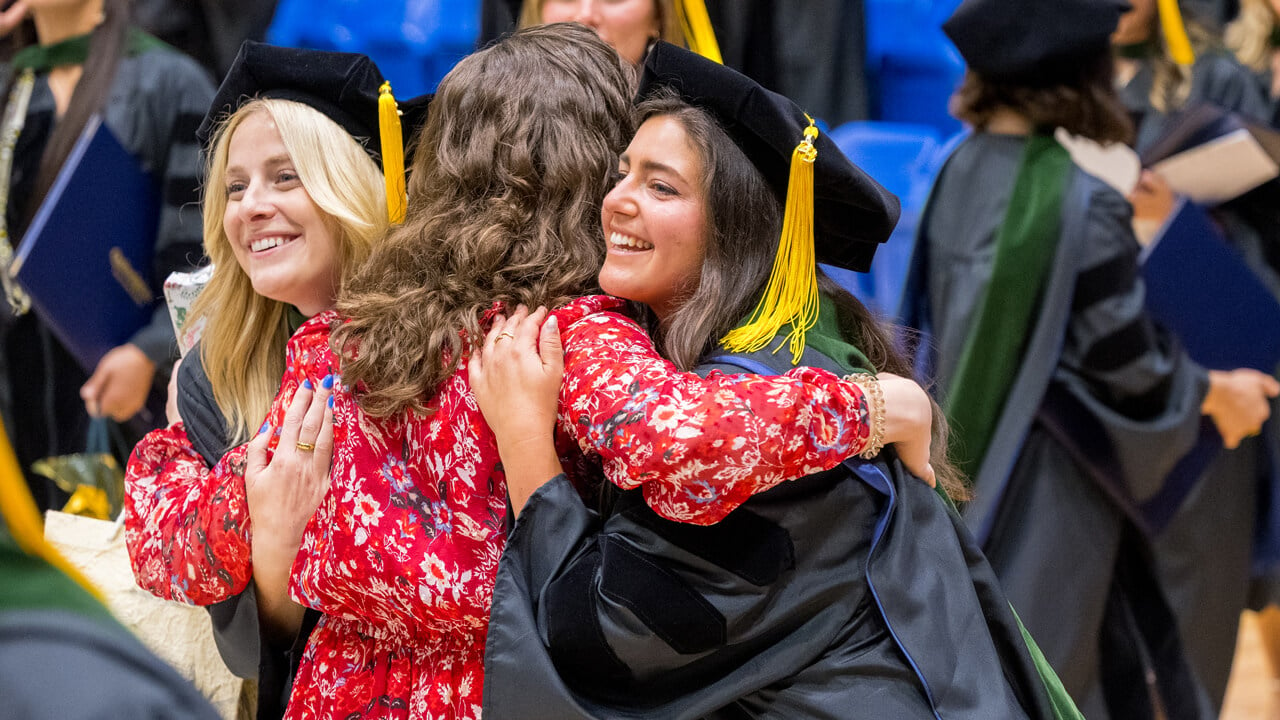 A guest hugs a graduate in congratulations