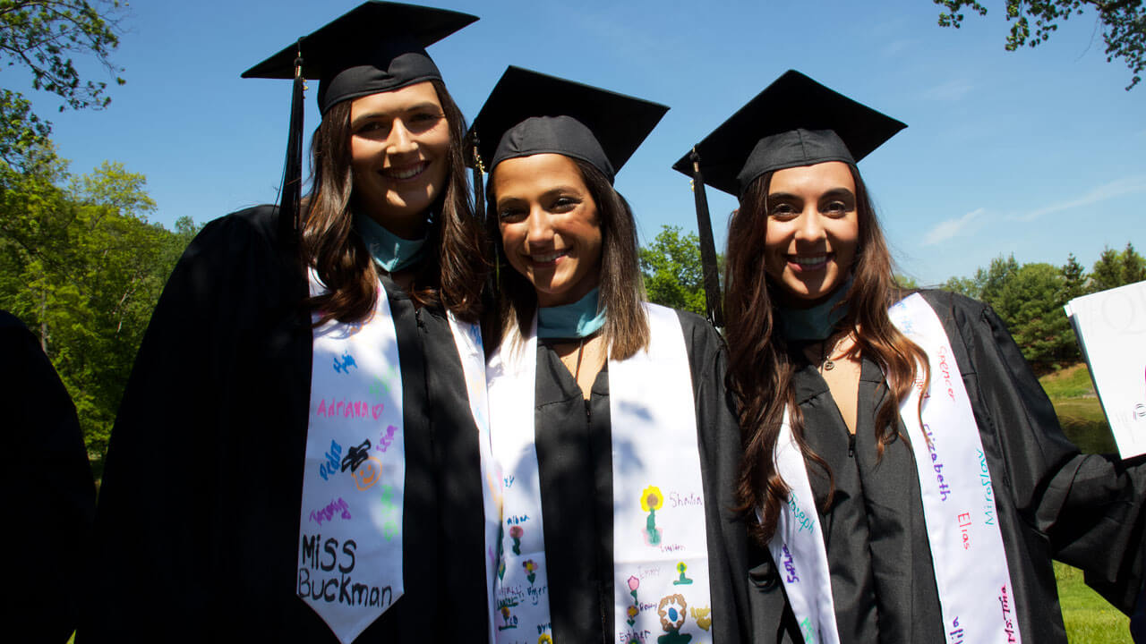 Graduates smiling and decorated stoles with students name