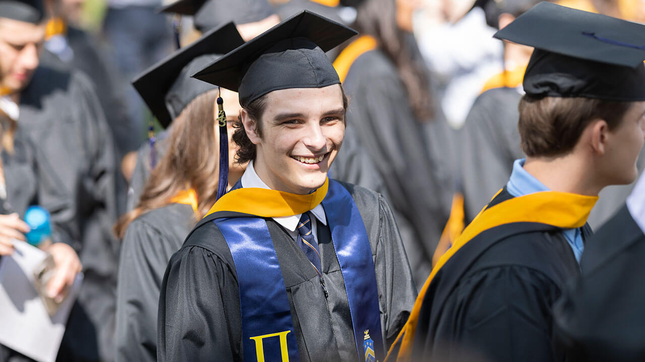 Business student smiling in his cap and gown