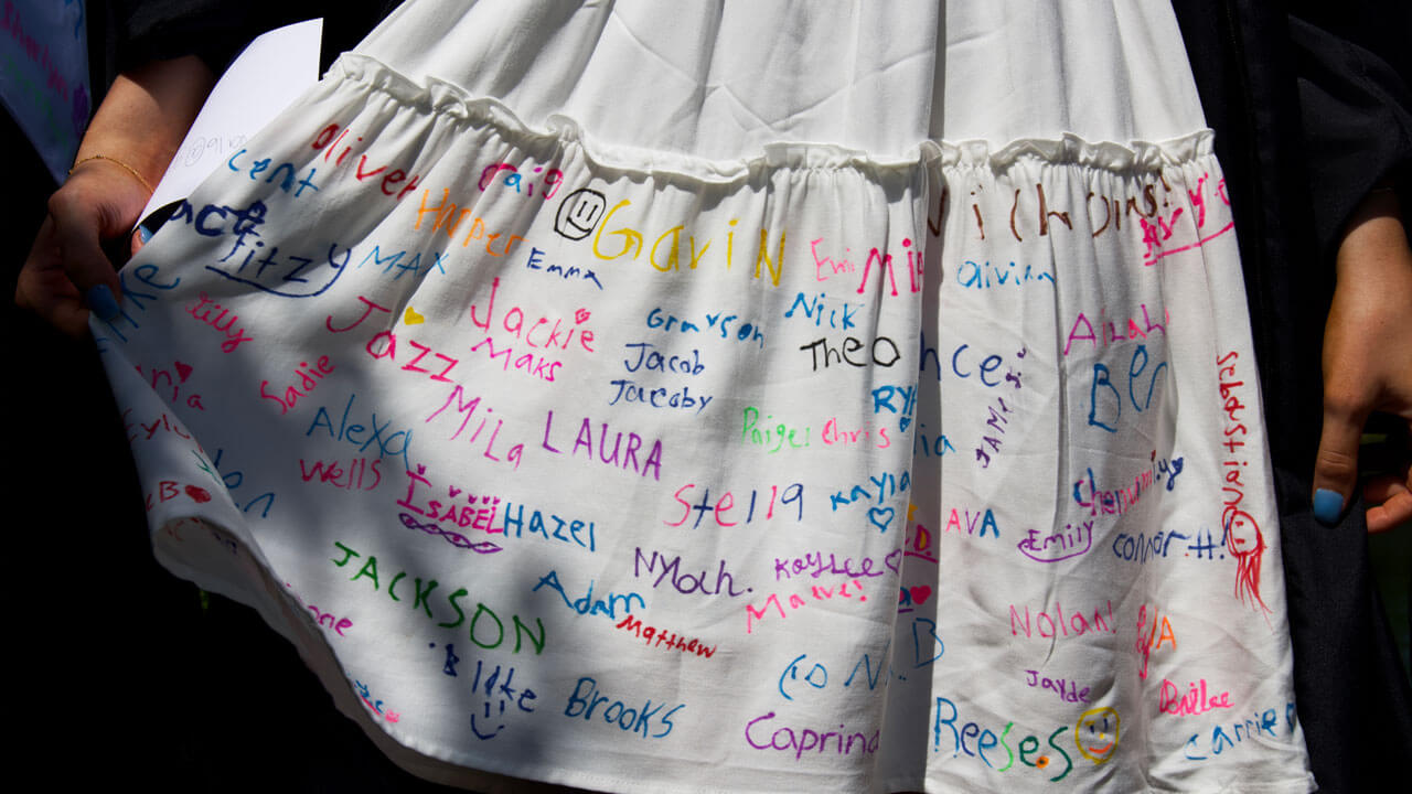 Graduates white dress written in colorful letters of students names