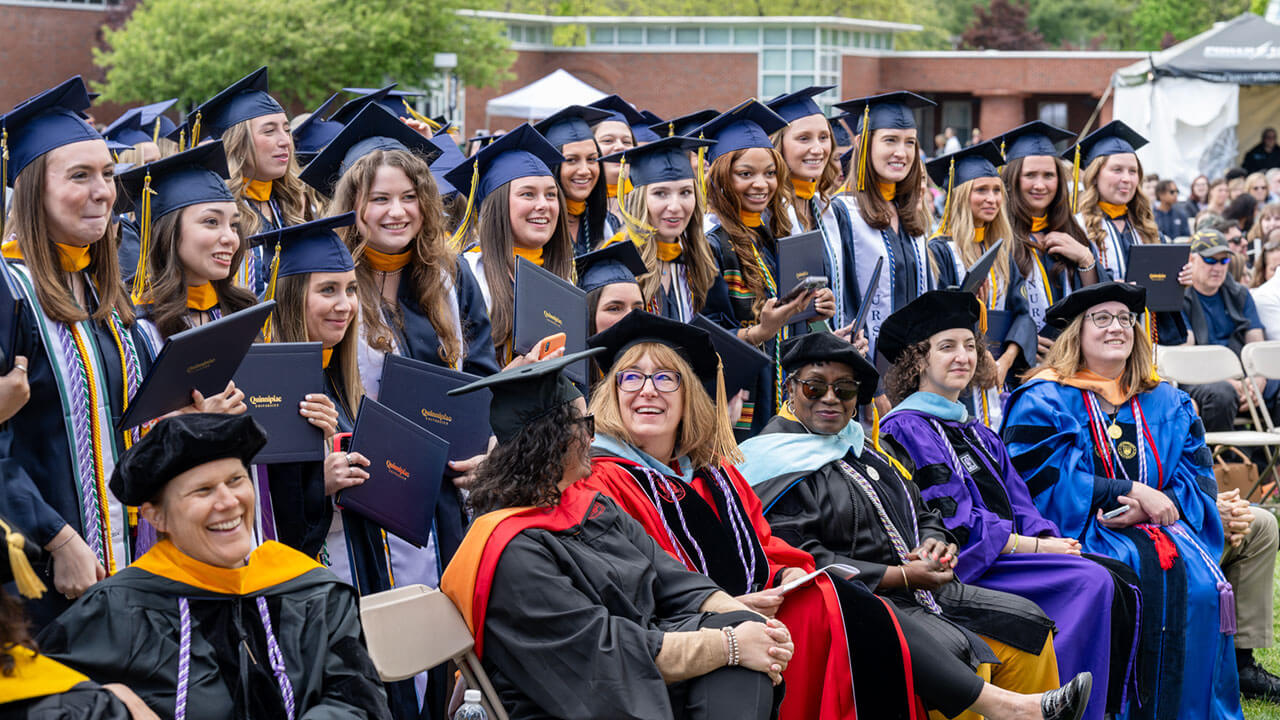 row of graduates poses behind professors